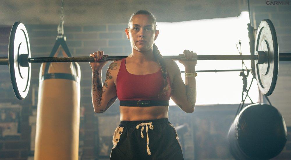 women squatting a barbell wearing a chest heart rate monitor 